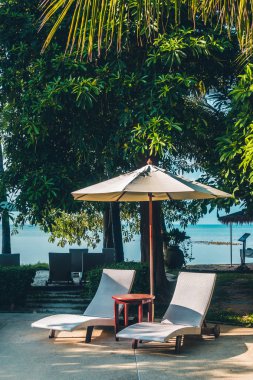 Güzel lüks otel ve tatil seyahat ve tatil için sandalye ve şemsiye ile açık yüzme havuzu
