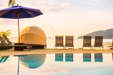 Şemsiye ve lüks otel ve gündoğumu zaman seyahat ve tatil için Resort'ta yüzme havuzu etrafında sandalye ile güzel açık görünüm