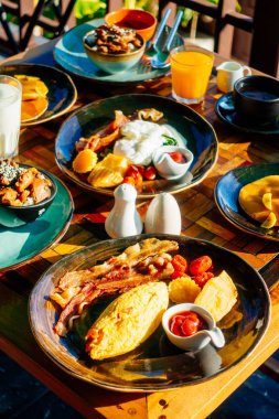 Sağlıklı kahvaltı seti yumurta pastırma ile portakal suyu süt ekmek kahve ve diğer ahşap masada krep