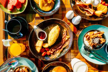 Sağlıklı kahvaltı seti yumurta pastırma ile portakal suyu süt ekmek kahve ve diğer ahşap masada krep