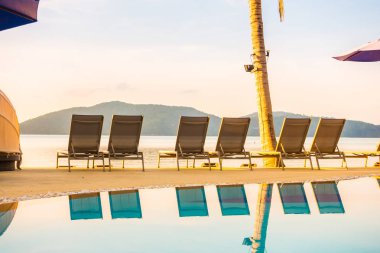 Şemsiye ve lüks otel ve gündoğumu zaman seyahat ve tatil için Resort'ta yüzme havuzu etrafında sandalye ile güzel açık görünüm