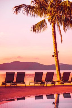 Şemsiye ve lüks otel ve gündoğumu zaman seyahat ve tatil için Resort'ta yüzme havuzu etrafında sandalye ile güzel açık görünüm