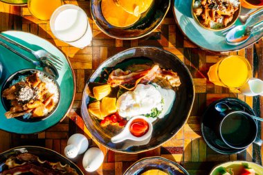 Sağlıklı kahvaltı seti yumurta pastırma ile portakal suyu süt ekmek kahve ve diğer ahşap masada krep