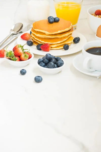 Healthy Breakfast set with Pancake and Granola with blueberry and strawberry and black coffee , Milk and Orange juice on white stone table background