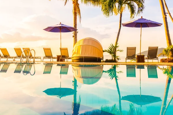 Şemsiye ve lüks otel ve gündoğumu zaman seyahat ve tatil için Resort'ta yüzme havuzu etrafında sandalye ile güzel açık görünüm