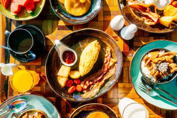 Sağlıklı kahvaltı seti yumurta pastırma ile portakal suyu süt ekmek kahve ve diğer ahşap masada krep