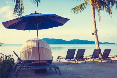 Şemsiye ve lüks otel ve gündoğumu zaman seyahat ve tatil için Resort'ta yüzme havuzu etrafında sandalye ile güzel açık görünüm