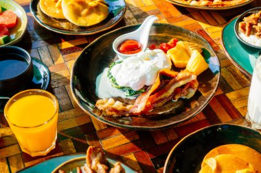 Sağlıklı kahvaltı seti yumurta pastırma ile portakal suyu süt ekmek kahve ve diğer ahşap masada krep