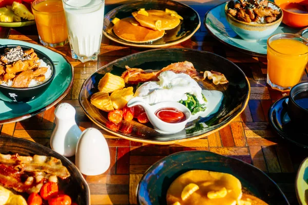 Sağlıklı kahvaltı seti yumurta pastırma ile portakal suyu süt ekmek kahve ve diğer ahşap masada krep