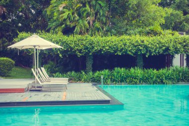 Güzel lüks şemsiye ve sandalye otel ve seyahat ve tatil için tatil yüzme havuzunda çevresinde