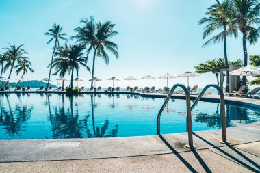 Güzel tropikal plaj ve deniz şemsiyesi ve sandalyesi otel tatil ve tatil için yüzme havuzunda.