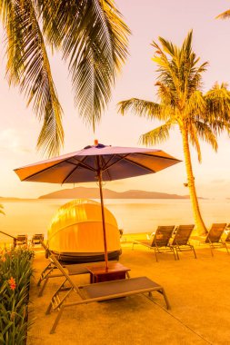 Şemsiye ve lüks otel ve gündoğumu zaman seyahat ve tatil için Resort'ta yüzme havuzu etrafında sandalye ile güzel açık görünüm