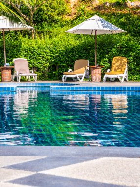 Şemsiye ve sandalye etrafında lüks otel ve resort tatil ve seyahat için açık yüzme havuzu