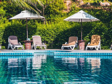 Şemsiye ve sandalye etrafında lüks otel ve resort tatil ve seyahat için açık yüzme havuzu