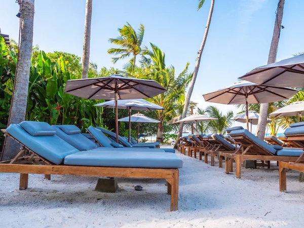 Şemsiye ve sandalyenin üstüne Hindistan cevizi hurma ağacının seyahat ve tatil etrafında mavi gökyüzü ile plaj ve okyanus