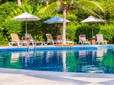 Şemsiye ve sandalye etrafında lüks otel ve resort tatil ve seyahat için açık yüzme havuzu