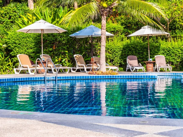 Şemsiye ve sandalye etrafında lüks otel ve resort tatil ve seyahat için açık yüzme havuzu