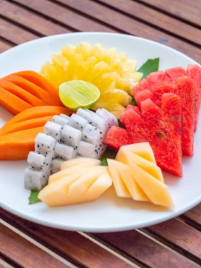 Coloful ahşap masa - sağlıklı gıda stil üzerinde beyaz tabak içinde birçok meyve