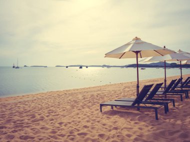 Şemsiye ve tropikal plaj deniz ve okyanus gündoğumu zaman seyahat ve tatil için sandalye