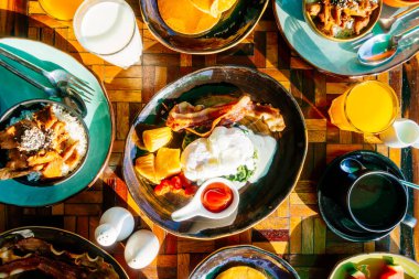 Sağlıklı kahvaltı seti yumurta pastırma ile portakal suyu süt ekmek kahve ve diğer ahşap masada krep