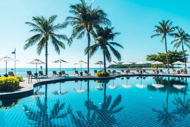 Güzel tropikal plaj ve deniz şemsiyesi ve sandalyesi otel tatil ve tatil için yüzme havuzunda.