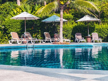 Şemsiye ve sandalye etrafında lüks otel ve resort tatil ve seyahat için açık yüzme havuzu