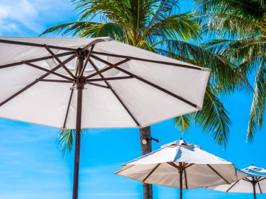 Hindistan cevizi hurma ağacı ile deniz okyanus seyahat ve tatil için mavi gökyüzü arka plan üzerinde Beyaz şemsiye