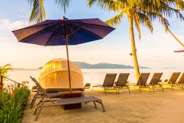 Şemsiye ve lüks otel ve gündoğumu zaman seyahat ve tatil için Resort'ta yüzme havuzu etrafında sandalye ile güzel açık görünüm