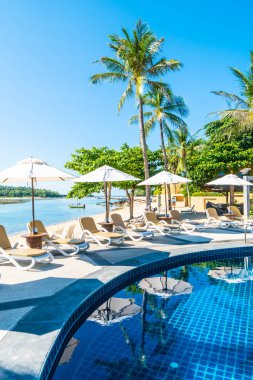 Güzel tropikal plaj ve deniz şemsiyesi ve sandalyesi otel tatil ve tatil için yüzme havuzunda.