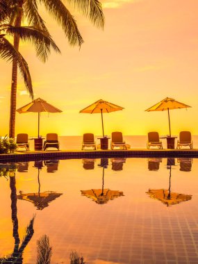 Şemsiye ve sandalye etrafında lüks otel ve resort tatil ve seyahat için açık yüzme havuzu