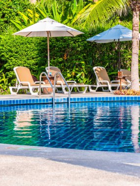 Şemsiye ve sandalye etrafında lüks otel ve resort tatil ve seyahat için açık yüzme havuzu