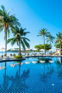 Güzel tropikal plaj ve deniz şemsiyesi ve sandalyesi otel tatil ve tatil için yüzme havuzunda.