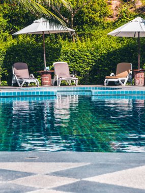 Şemsiye ve sandalye etrafında lüks otel ve resort tatil ve seyahat için açık yüzme havuzu