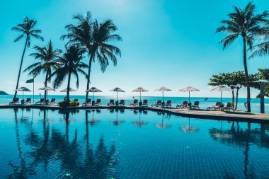 Güzel tropikal plaj ve deniz şemsiyesi ve sandalyesi otel tatil ve tatil için yüzme havuzunda.