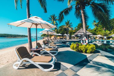 Güzel tropikal plaj ve deniz şemsiyesi ve sandalyesi otel tatil ve tatil için yüzme havuzunda.