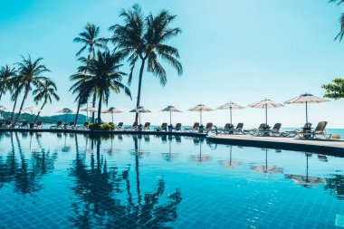 Güzel tropikal plaj ve deniz şemsiyesi ve sandalyesi otel tatil ve tatil için yüzme havuzunda.