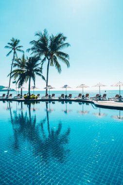 Güzel tropikal plaj ve deniz şemsiyesi ve sandalyesi otel tatil ve tatil için yüzme havuzunda.