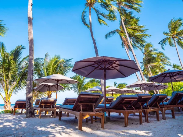 Şemsiye ve sandalyenin üstüne Hindistan cevizi hurma ağacının seyahat ve tatil etrafında mavi gökyüzü ile plaj ve okyanus