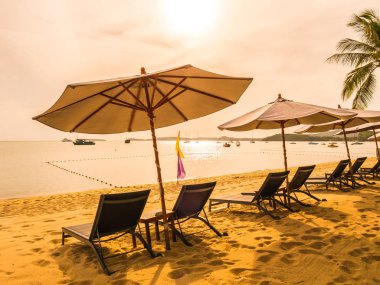 Şemsiye ve tropikal plaj deniz ve okyanus gündoğumu zaman seyahat ve tatil için sandalye
