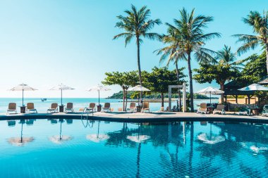 Güzel tropikal plaj ve deniz şemsiyesi ve sandalyesi otel tatil ve tatil için yüzme havuzunda.