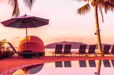 Şemsiye ve lüks otel ve gündoğumu zaman seyahat ve tatil için Resort'ta yüzme havuzu etrafında sandalye ile güzel açık görünüm