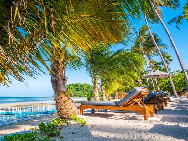 Şemsiye ve sandalyenin üstüne Hindistan cevizi hurma ağacının seyahat ve tatil etrafında mavi gökyüzü ile plaj ve okyanus