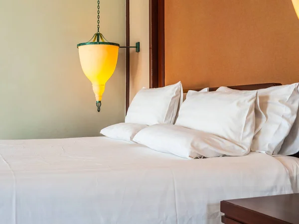 Comfortable pillow on bed with light lamp decoration in hotel bedroom