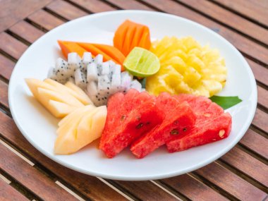 Coloful ahşap masa - sağlıklı gıda stil üzerinde beyaz tabak içinde birçok meyve