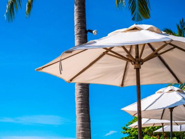 Hindistan cevizi hurma ağacı ile deniz okyanus seyahat ve tatil için mavi gökyüzü arka plan üzerinde Beyaz şemsiye