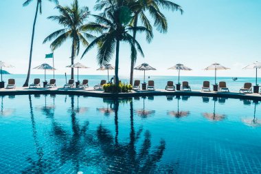 Güzel tropikal plaj ve deniz şemsiyesi ve sandalyesi otel tatil ve tatil için yüzme havuzunda.