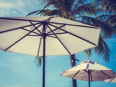 Hindistan cevizi hurma ağacı ile deniz okyanus seyahat ve tatil için mavi gökyüzü arka plan üzerinde Beyaz şemsiye