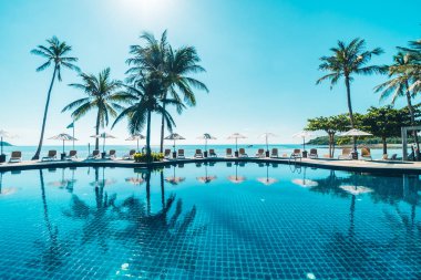 Güzel tropikal plaj ve deniz şemsiyesi ve sandalyesi otel tatil ve tatil için yüzme havuzunda.