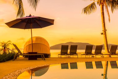 Şemsiye ve lüks otel ve gündoğumu zaman seyahat ve tatil için Resort'ta yüzme havuzu etrafında sandalye ile güzel açık görünüm