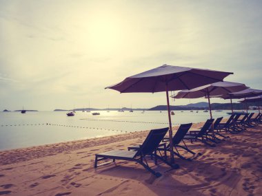 Şemsiye ve tropikal plaj deniz ve okyanus gündoğumu zaman seyahat ve tatil için sandalye